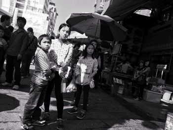 Rear view of people standing on street in city