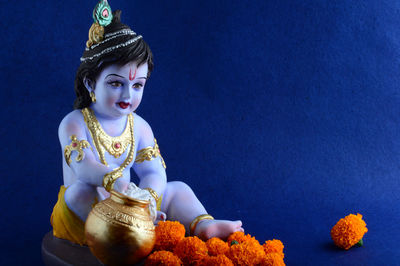 Close-up of boy with statue against blue background