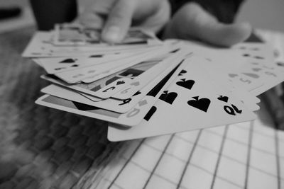 Close-up of person hands holding playing cards on table