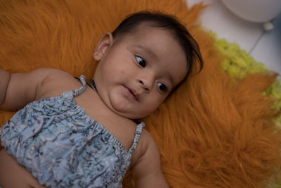 Portrait of cute baby lying on bed at home