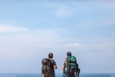 Rear view of men looking at sea against sky