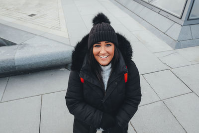 Portrait of smiling young woman standing in snow