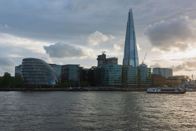 Sea by modern buildings against sky in city