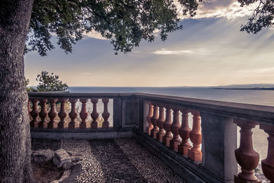 Railing by sea against sky during sunset