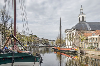 Sailboats moored on river against buildings in city