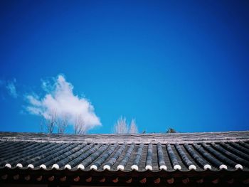 Low angle view of roof and building against blue sky
