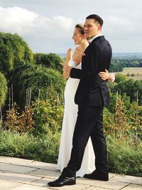 Couple standing by plants against trees