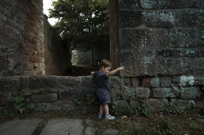 Side view of young man standing against wall