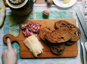 High angle view of hand holding bread on cutting board