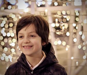 Smiling boy looking away against illuminated lights