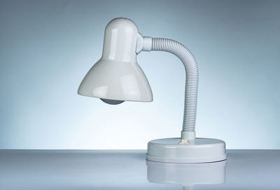 Close-up of electric lamp on table against white background