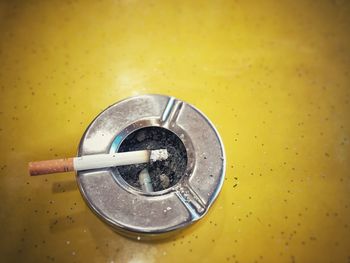 Close-up of cigarette on ashtray at yellow table