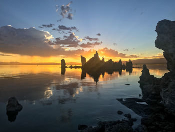 Silhouette of rocks on sea during sunset