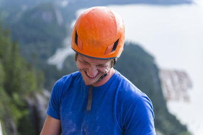 Climber with helmet smiling and laughing looking down above water