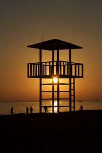 Silhouette people on beach against sky during sunset