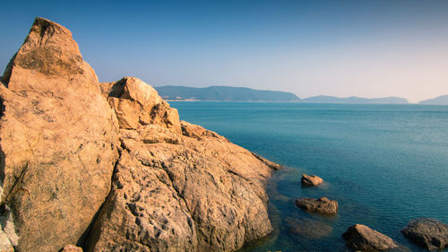 Scenic view of sea and mountains against clear sky