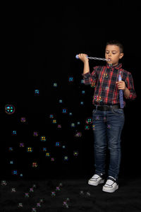 Full length of boy standing against black background