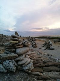 Stack of stones on beach against sky during sunset