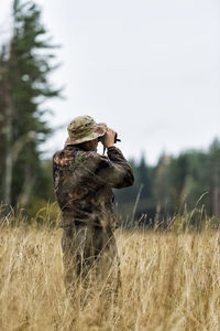 Teenager with binoculars watching forest