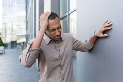 Portrait of young man standing against wall