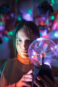 Close-up portrait of woman holding illuminated lighting equipment in room