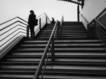 Low angel view of people standing on staircase against sky