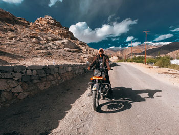 Man riding bicycle on road against sky