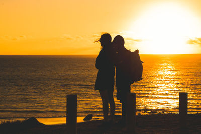 Silhouette people standing on pier against sky during sunset