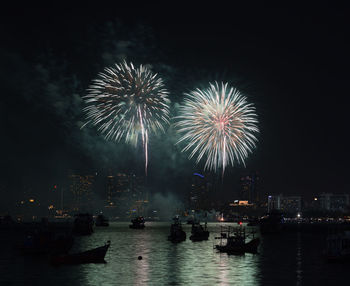 Firework display in city against sky at night