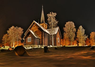 Houses by trees against sky at night during winter