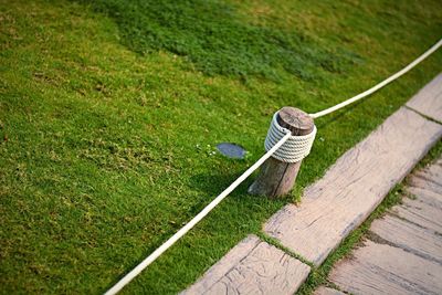 High angle view of rope tied to bollard on field