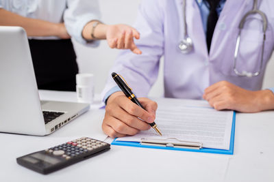 Midsection of man using mobile phone on table