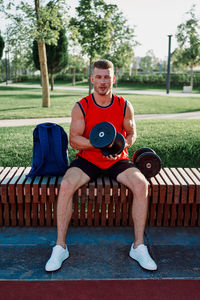 Portrait of young man sitting on sofa at park