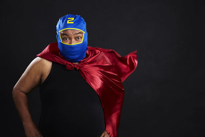 Portrait of man standing against black background