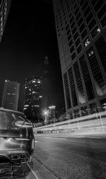 Cars on road by illuminated buildings in city at night