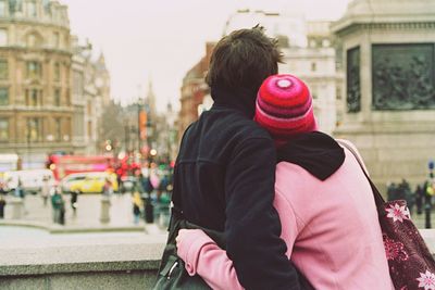 Rear view of couple embracing on street