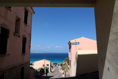 Buildings by sea against blue sky