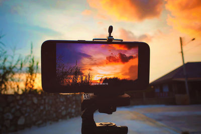 Orange sky seen through mobile screen during sunset