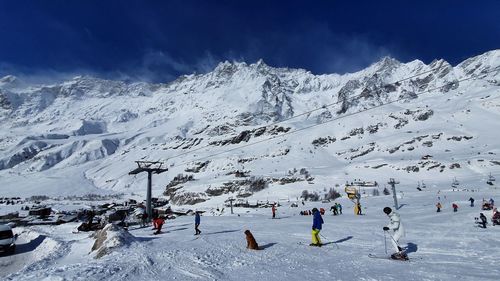 People on snowcapped mountain against sky