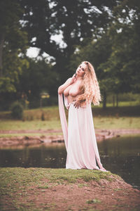 Portrait of young woman standing against tree