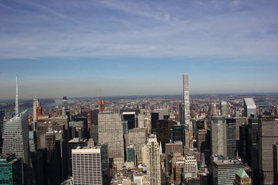 Aerial view of buildings in city against cloudy sky