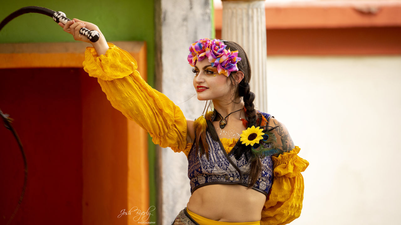 yellow, one person, women, adult, clothing, dancing, flower, young adult, arts culture and entertainment, traditional clothing, person, fashion accessory, headwear, female, lifestyles, waist up, flowering plant, fashion, performance art, arm, standing, indoors, nature, smiling, performing arts, headdress, portrait, emotion, holding, performance, happiness, architecture, arms raised, costume