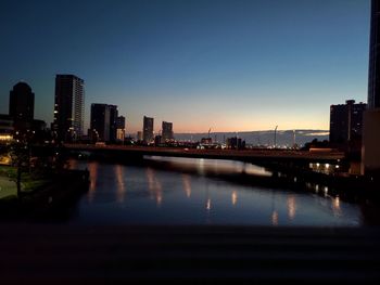 River by illuminated buildings against clear sky