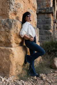 Low angle view of young man sitting on rock