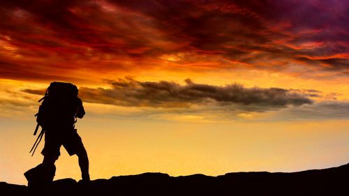 Silhouette of person standing on landscape against cloudy sky