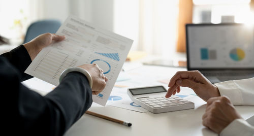 Midsection of business colleagues working on table