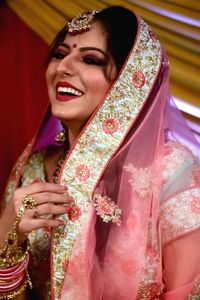 Woman in sari laughing while looking away during wedding