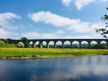 Arch bridge over river against sky