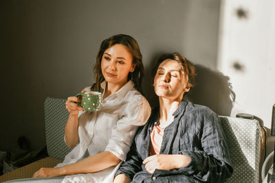 Two young women on sofa, resting with cup of tea