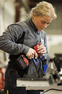 Woman using drilling machine in factory